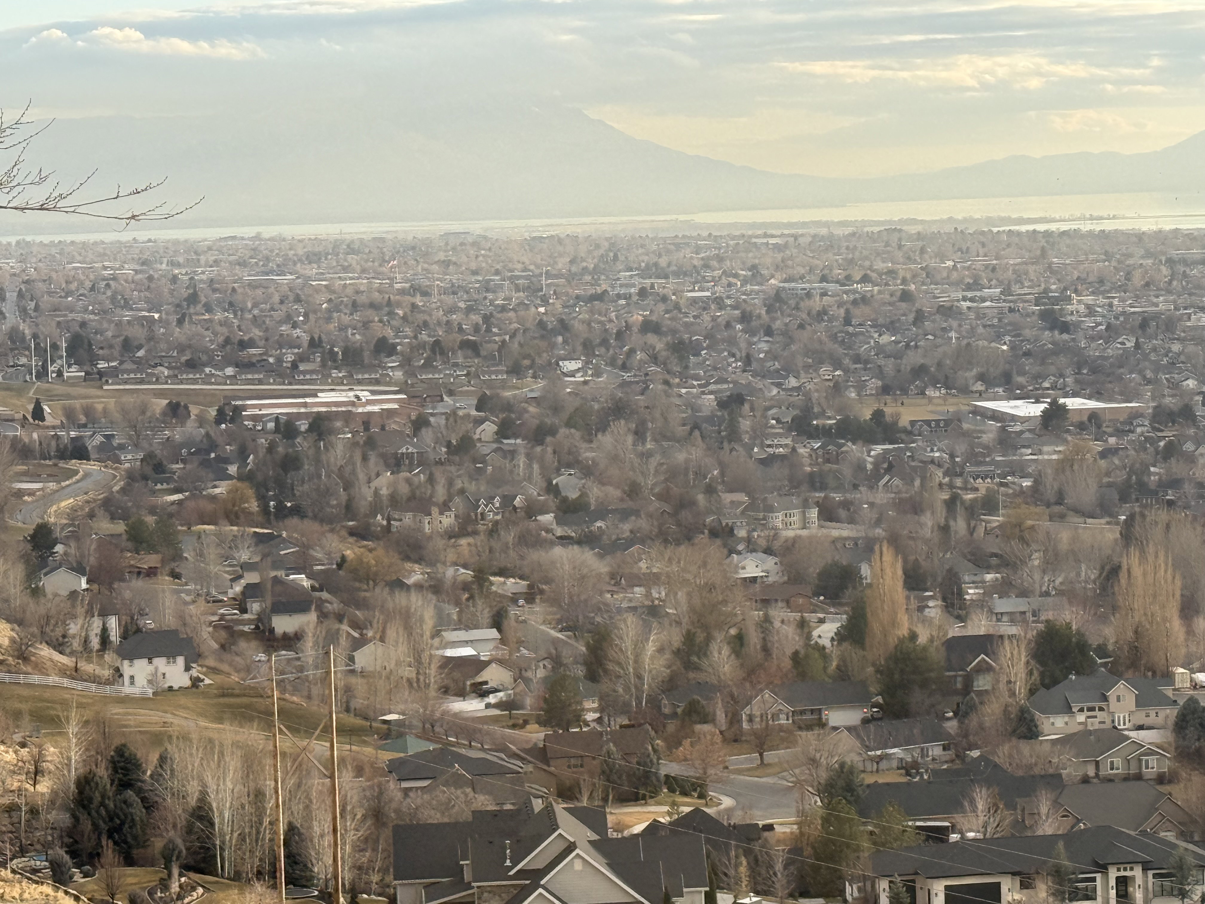 Expansive panoramic landscape featuring a distant body of water, distant mountains, and a vast residential area
