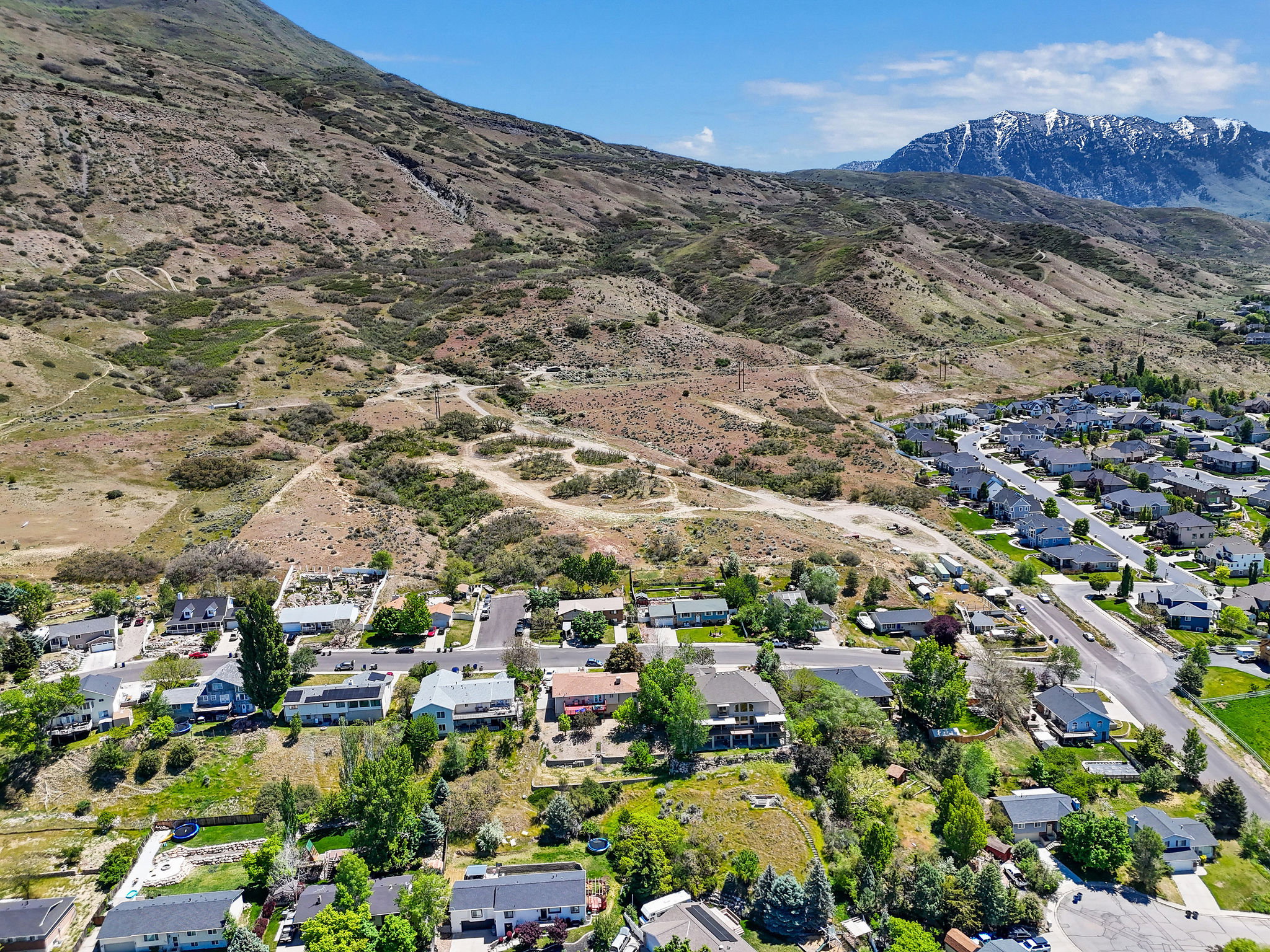 Aerial perspective showcasing residential properties nestled at the base of a rugged mountain range
