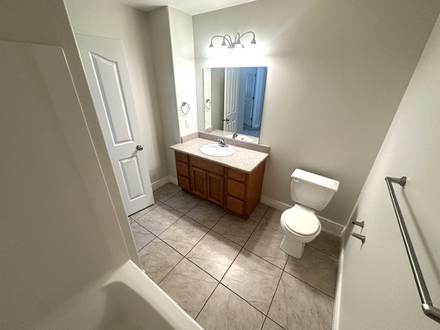 Full bathroom featuring a single vanity with wood cabinetry, a light-toned countertop, and an integrated sink