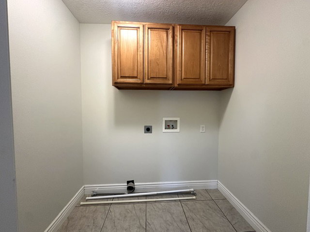 Utility room featuring overhead wood-finish cabinetry, neutral wall tones, and tiled flooring