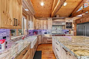 Spacious kitchen featuring natural wood cabinetry and exposed beam ceiling