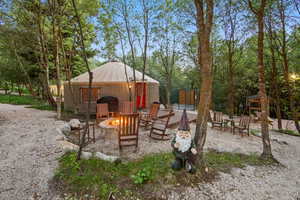 Yurt structure with a red entry door, surrounded by mature trees