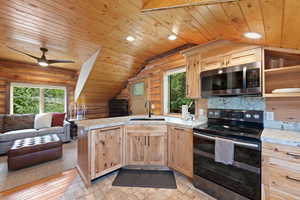 Open-concept kitchen featuring wood-finish cabinetry, light-colored countertops, and stainless steel appliances
