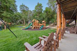 Expansive grassy lawn bordered by mature trees, featuring a multi-level playset with slides
