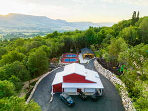 Expansive property featuring a red and white barn-style structure, a paved driveway, and a sports court