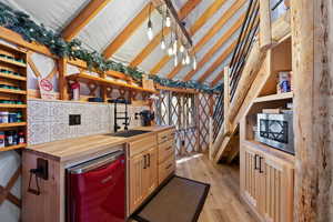 Well-appointed kitchen area featuring light wood cabinetry, a wood-finish countertop, and a black sink with a matching faucet