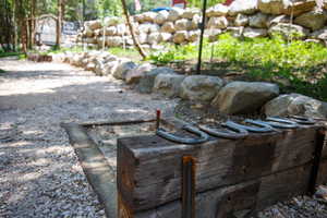 Outdoor recreation area featuring a gravel surface, wood timber edging, and a natural stone retaining wall
