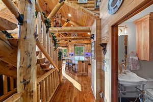 Interior showcasing rich wood-finish flooring, exposed log beam construction, a natural wood staircase, and a visible kitchen island with bar seating