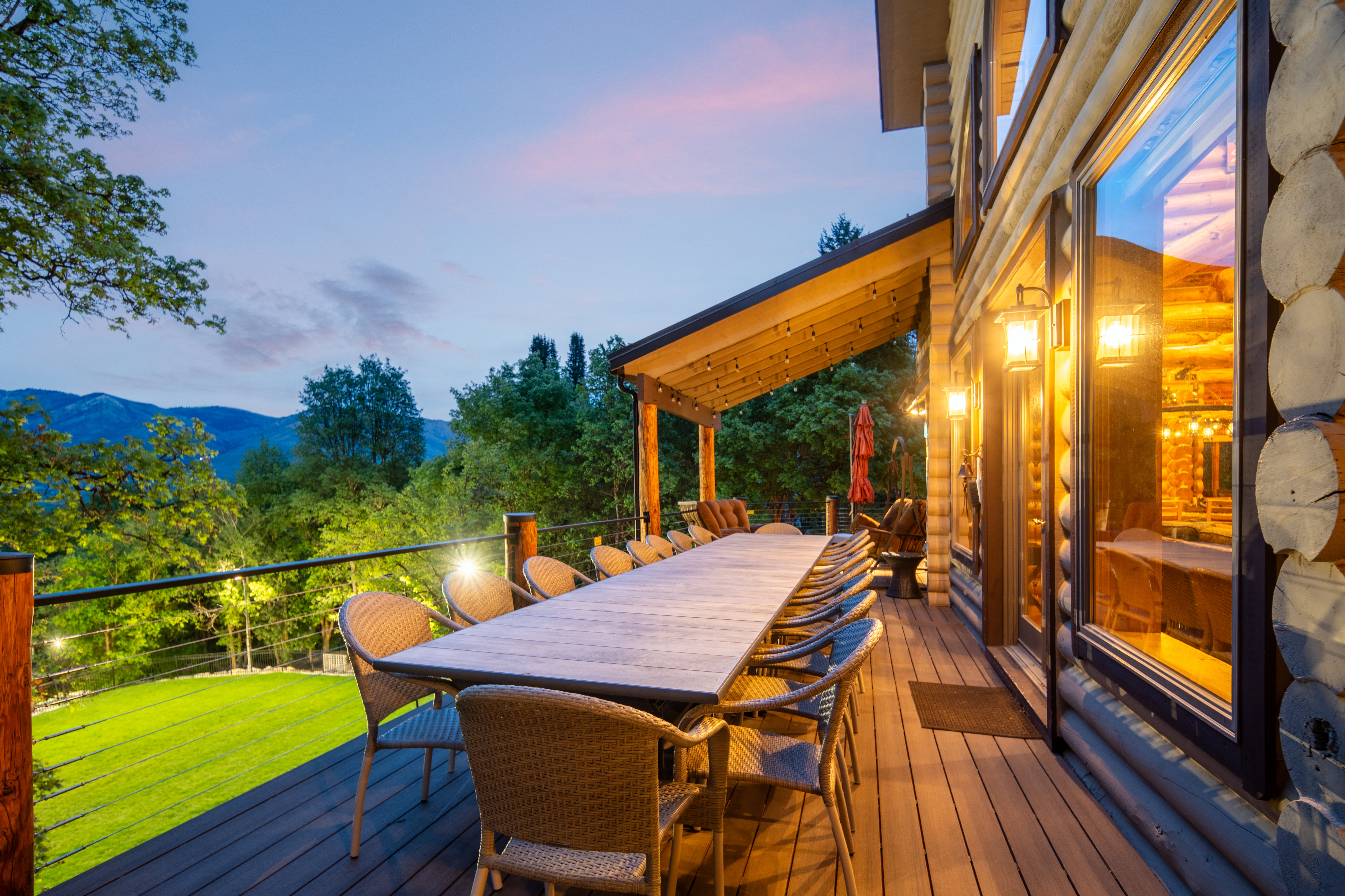Expansive outdoor deck featuring composite decking, a covered patio area with string lighting, and a durable log-sided exterior