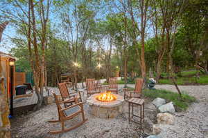 Stone fire pit surrounded by a gravel patio and mature trees