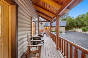 Expansive covered porch featuring a log construction, wood railing, and a matching wood ceiling