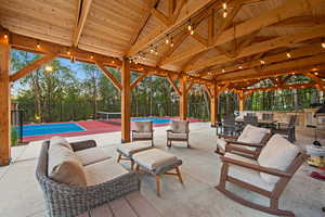 Expansive outdoor living area featuring a wood-beam vaulted ceiling and string lighting