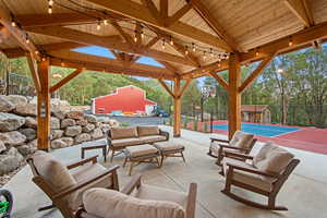 Expansive covered patio featuring a wood-beam ceiling, string lighting, and concrete flooring