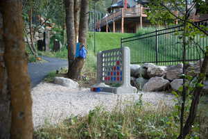 Landscaped outdoor area featuring a gravel surface, mature trees, and a paved pathway