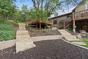 Stone steps leading to an elevated wood deck with cable railings