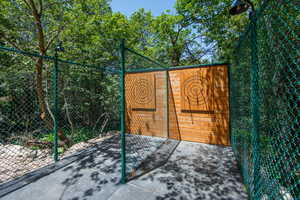 Dedicated outdoor recreation area featuring two wooden target boards, secured within a green chain-link enclosure, and illuminated by installed exterior lighting