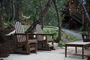 Paved patio area with Adirondack chairs, featuring string lighting overhead and a putting green visible in the background