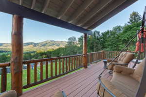Expansive outdoor deck featuring wood-finish flooring and log railing