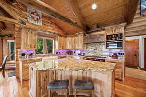 Gourmet kitchen featuring a large island with seating, a professional-grade range, built-in microwave, and ample natural wood cabinetry