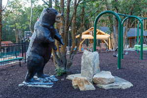 Sculptural bear figure anchors a landscaped area featuring natural stone elements and a dark ground cover