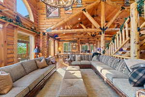 Vaulted wood-beamed ceilings with exposed log construction, a log staircase with open risers, and wood-finish flooring