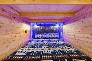 Wood-paneled room with integrated blue lighting and a recessed headboard featuring textured wood panels