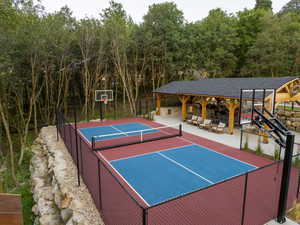 Multi-sport court with vibrant blue and red surfacing, fenced perimeter, and dual basketball hoops