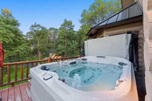 Outdoor hot tub on a wood deck featuring a rustic log railing