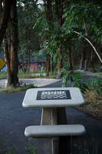 Freestanding concrete game table with an inlaid chessboard surface, positioned on a paved pathway