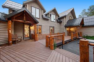 Expansive composite decking surrounds this log-sided residence featuring multiple gabled rooflines with dark metal roofing