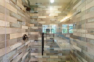Shower enclosure featuring multi-toned plank-style wall tiling and a frameless glass door