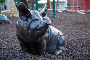 Sculptural pig figure situated on a dark wood chip surface