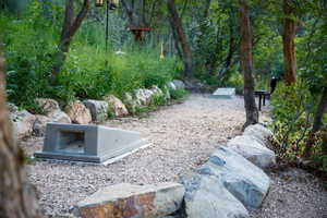 Gravel pathway bordered by natural stone, surrounded by mature trees and lush vegetation