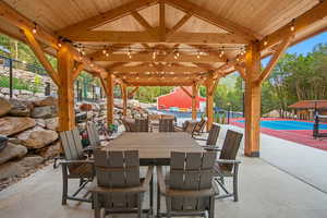 Expansive outdoor patio featuring a timber-framed pergola with exposed beams and string lighting