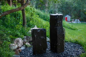 Two dark stone water features set on a bed of dark gravel