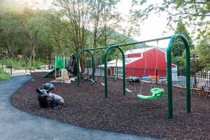 Outdoor play area featuring a swing set, slide, and rubber mulch surfacing