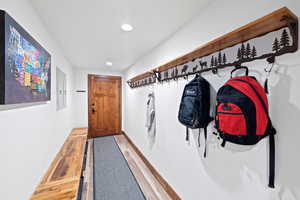 Entryway featuring a wood-panel door, built-in wooden bench, wood-finish flooring, recessed lighting, and a decorative wall-mounted coat rack