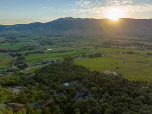 Expansive aerial perspective showcasing a mountainous landscape with verdant fields and dense tree coverage