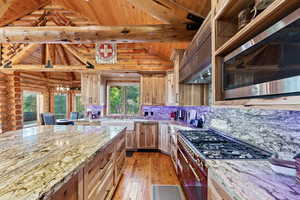 Kitchen featuring a large island with stone countertops, custom wood cabinetry, stainless steel appliances, and wood-finish flooring