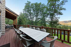 Expansive outdoor deck featuring a wooden railing, a covered porch area, and a log cabin style exterior