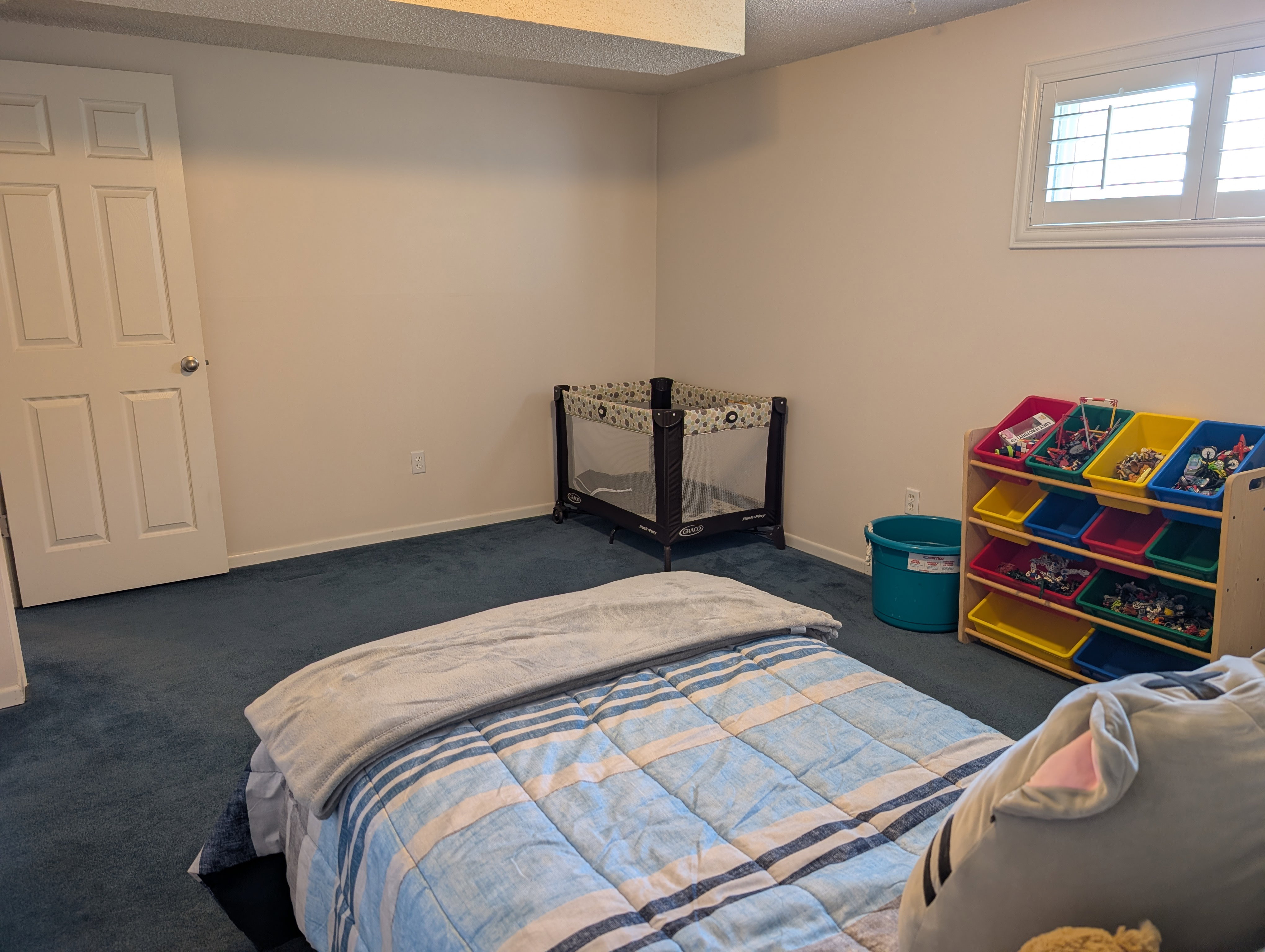 Bedroom with white interior door, neutral wall paint, white baseboards, and blue carpet flooring