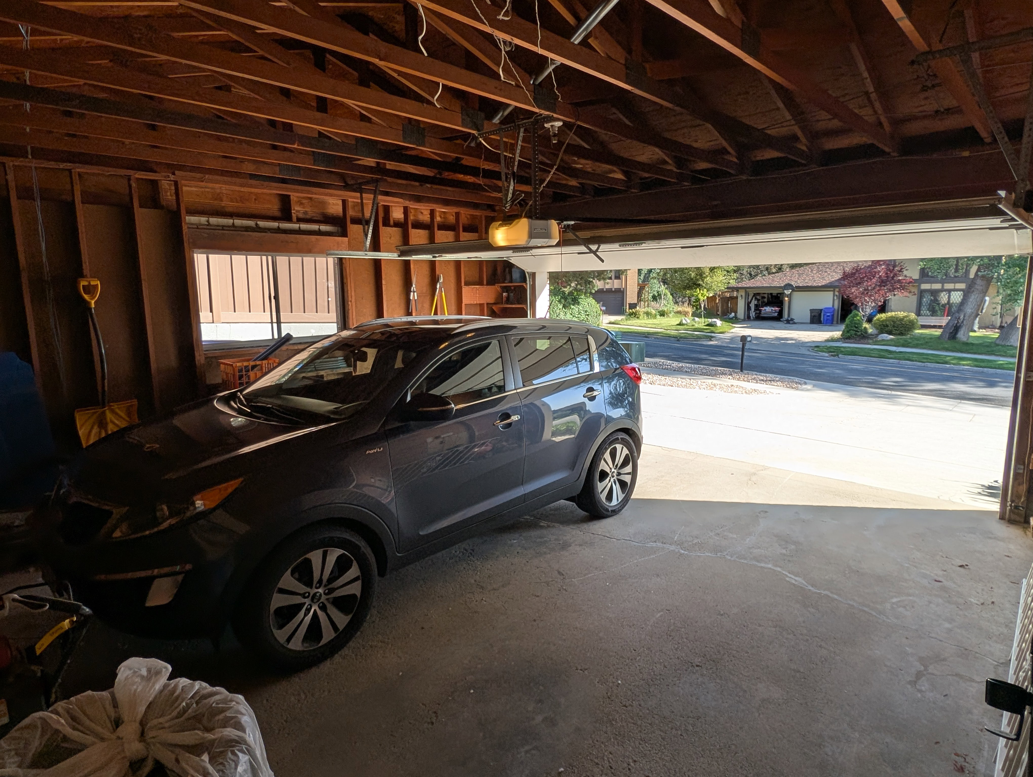 Attached garage featuring exposed wood framing and a concrete floor