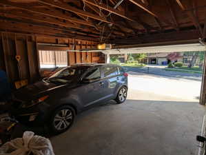 Attached garage featuring exposed wood framing and a concrete floor