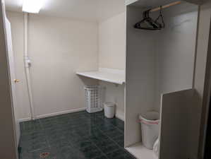 Laundry area featuring dark green square floor tiles, a built-in white countertop, and a clothes hanging rod within an alcove