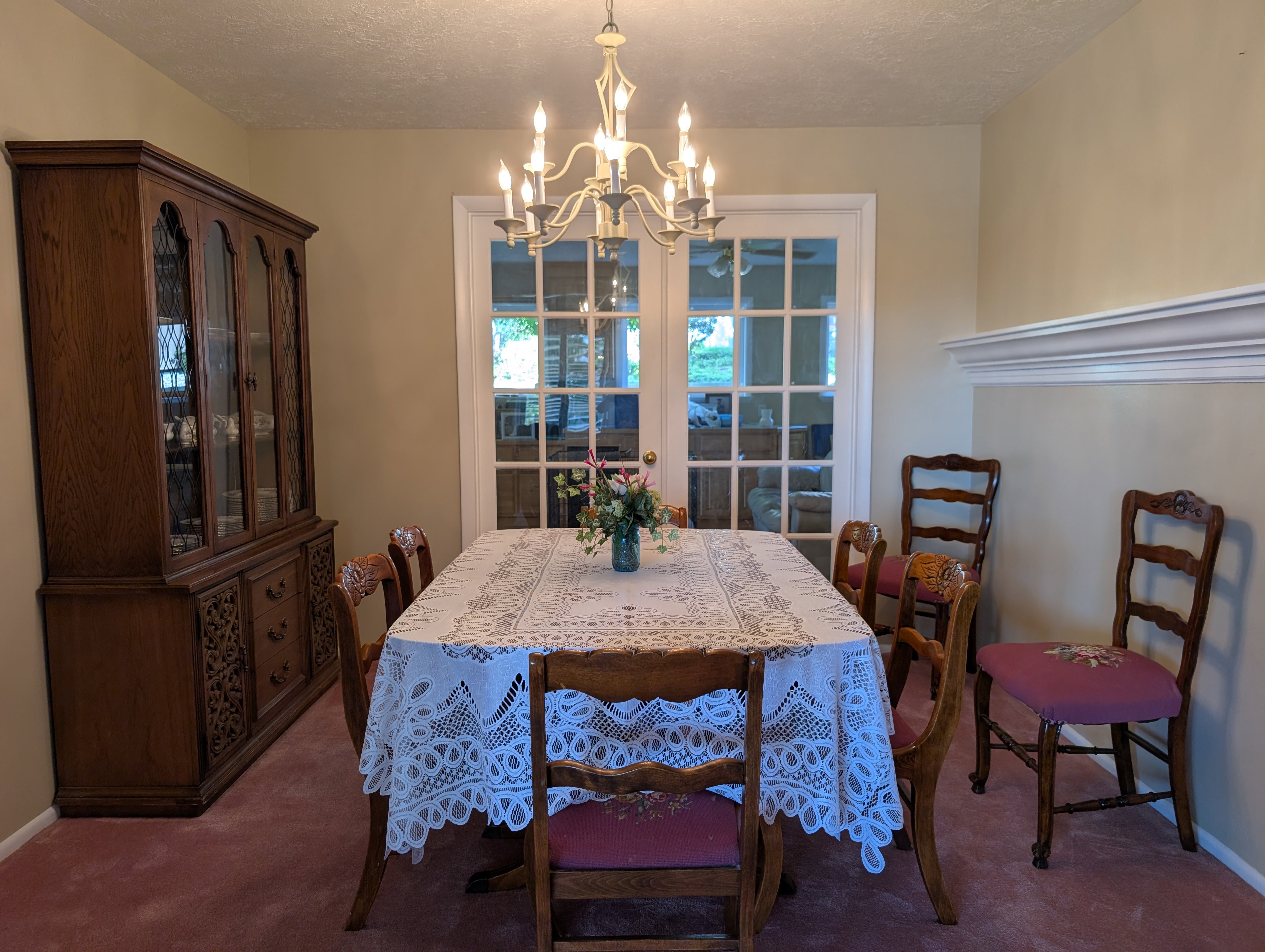 Dining area featuring a central chandelier, light-colored walls, and a decorative chair rail molding
