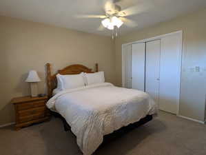 Carpeted bedroom featuring a ceiling fan with light fixture and bi-fold closet doors