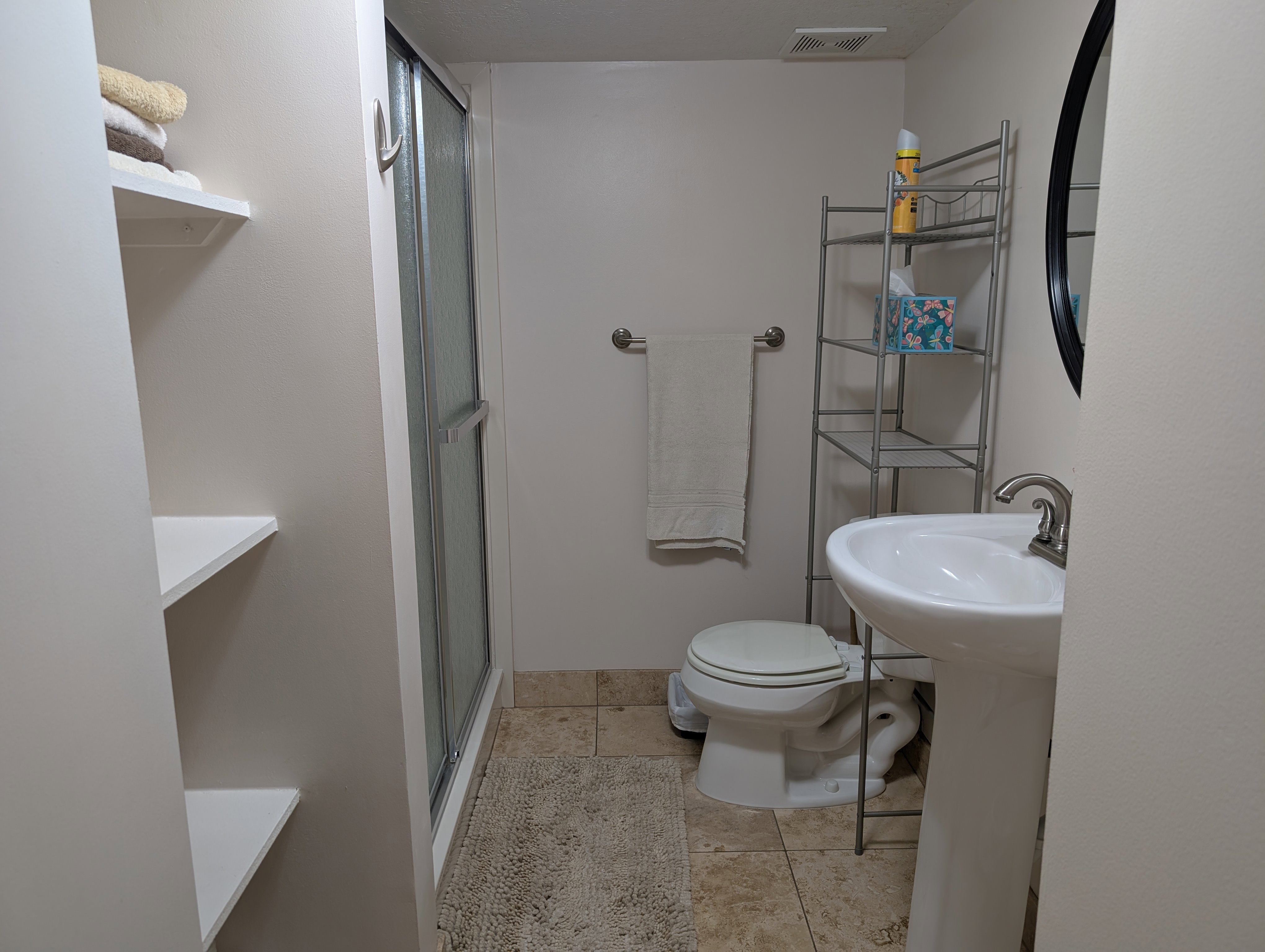 Bathroom featuring a pedestal sink with a brushed nickel faucet, a toilet, and a shower with a sliding glass door