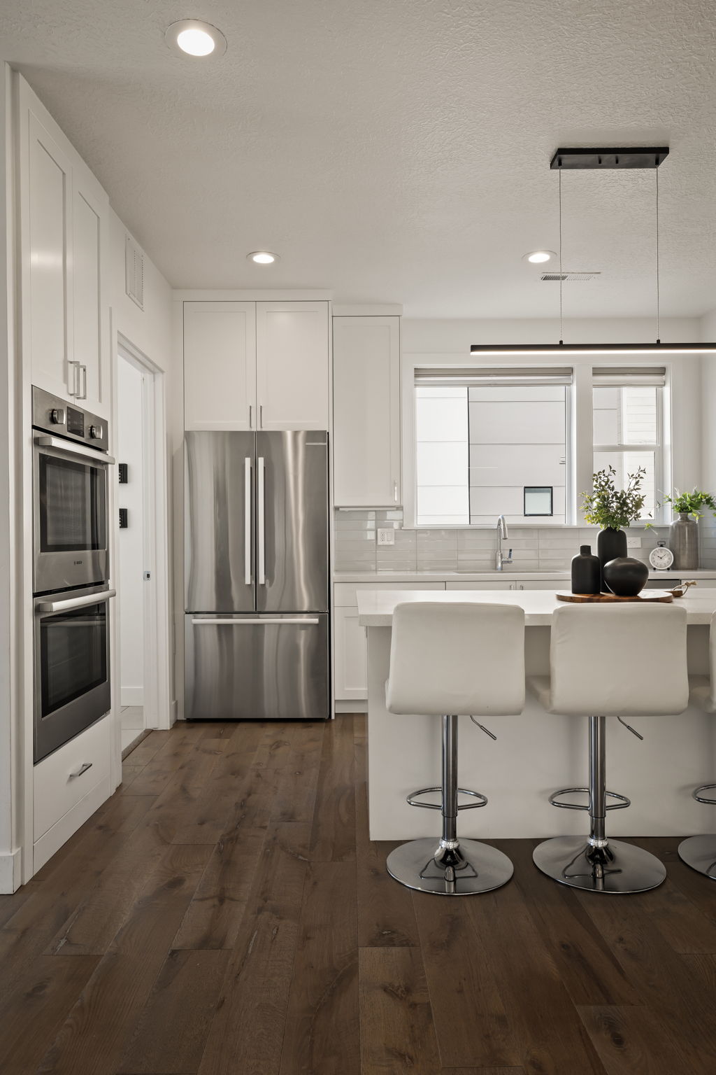 Kitchen featuring stainless steel appliances, white cabinetry, a kitchen breakfast bar, dark wood finished floors, and recessed lighting