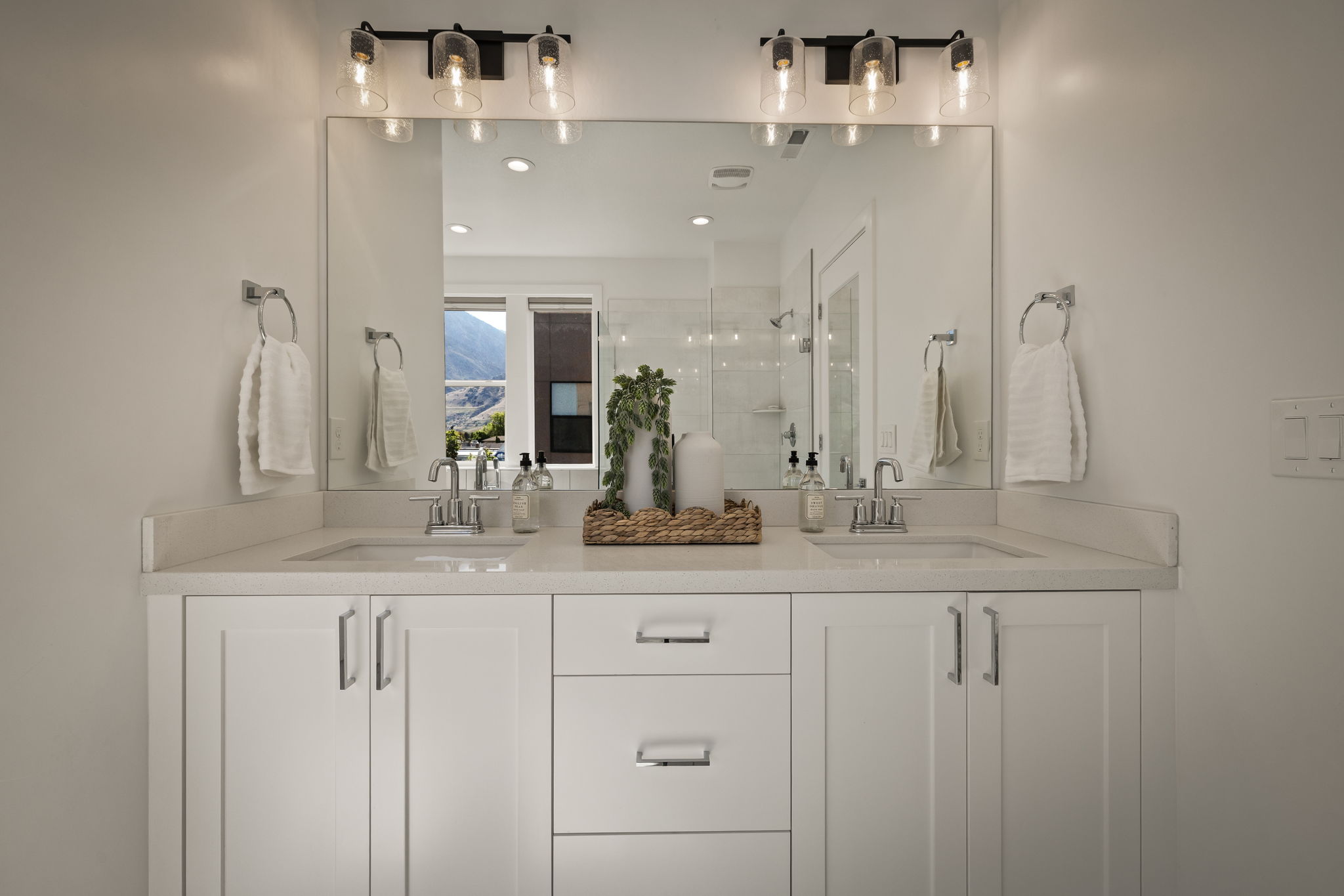 Bathroom featuring a shower stall, double vanity, and recessed lighting