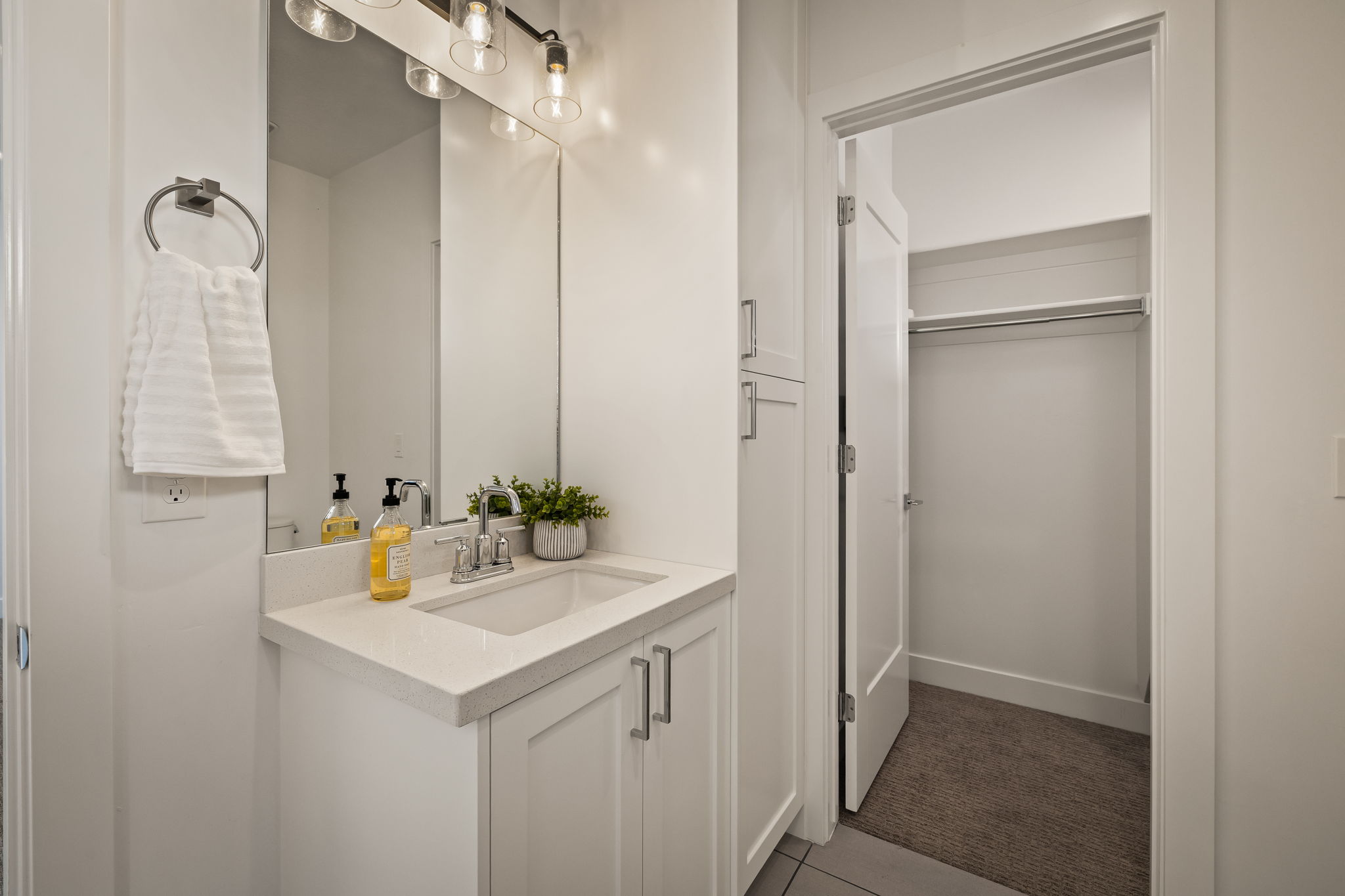 Bathroom with vanity, a walk in closet, dark tile patterned flooring, and dark carpet